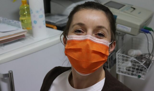 face mask, nurse, woman with mask, healthcare worker, orange mask, clinic, medical setting, safety, hospital, pandemic, protective gear, health professional, smiling eyes, female portrait, medical staff, friendly expression, covid-19, hygiene, healthcare environment, face protection, medical equipment, doctor, protective wear, indoor portrait